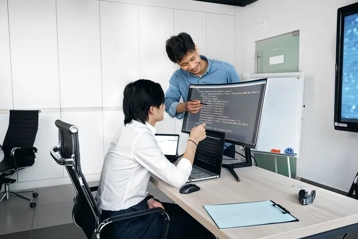 Two engineers working through a problem at a desk